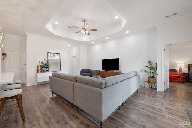 living room featuring a ceiling fan, recessed lighting, wood finished floors, a tray ceiling, and visible vents