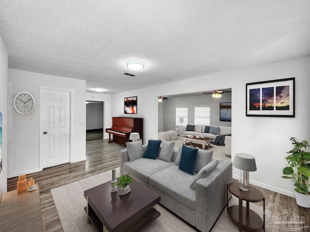 living room featuring a ceiling fan, visible vents, a textured ceiling, and wood finished floors