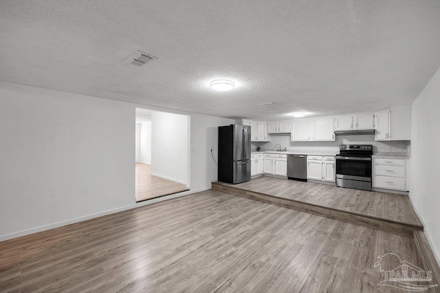 kitchen featuring under cabinet range hood, visible vents, light countertops, appliances with stainless steel finishes, and light wood finished floors