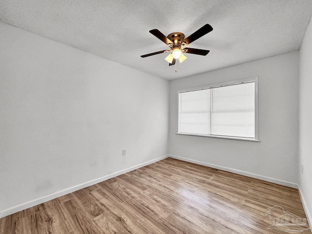 spare room featuring a textured ceiling, ceiling fan, wood finished floors, and baseboards