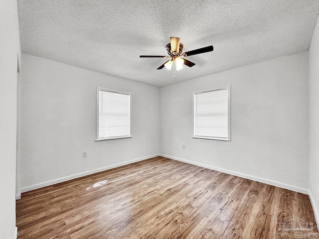 unfurnished room featuring baseboards, a ceiling fan, a wealth of natural light, and wood finished floors