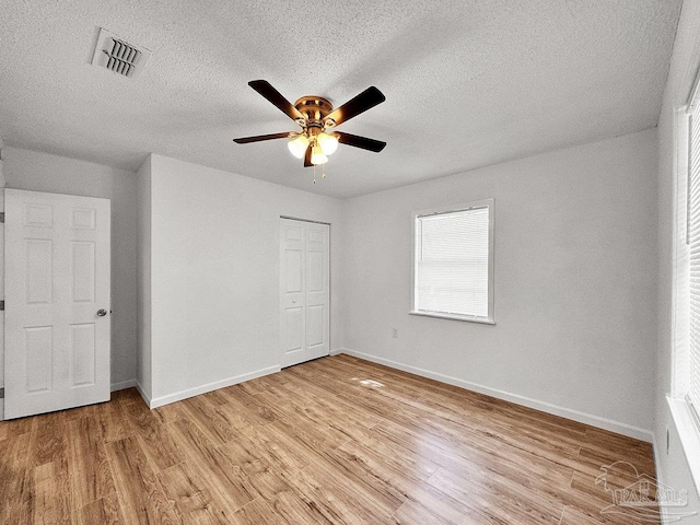 unfurnished bedroom with a closet, visible vents, baseboards, and light wood finished floors