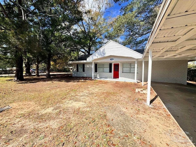 view of front facade with a carport, brick siding, and driveway