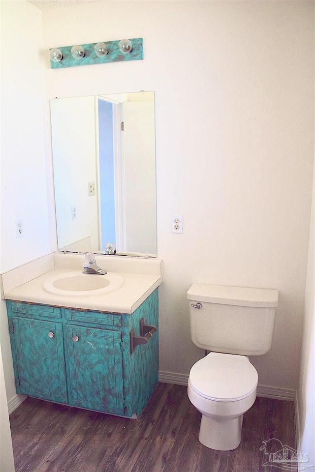 bathroom featuring baseboards, wood finished floors, toilet, and vanity
