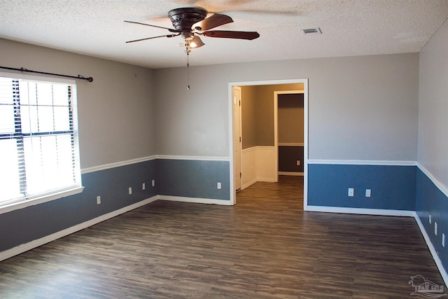 empty room featuring dark wood-type flooring, a textured ceiling, visible vents, and a ceiling fan