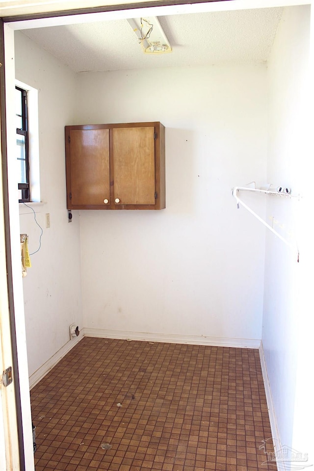 laundry area featuring baseboards and a textured ceiling