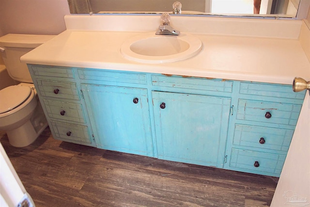 bathroom with wood finished floors, toilet, and vanity