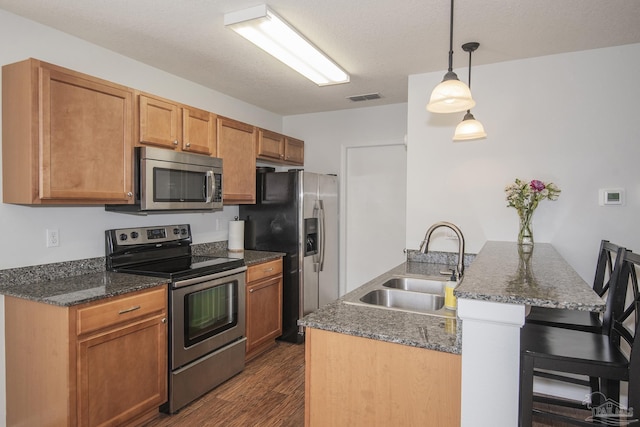 kitchen featuring pendant lighting, sink, stainless steel appliances, and dark stone countertops