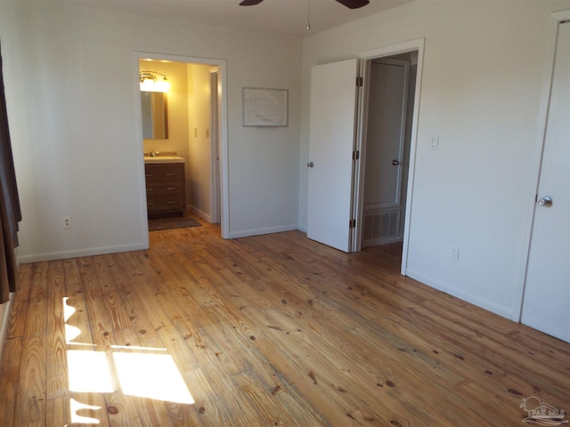 unfurnished bedroom with wood-type flooring, ensuite bathroom, sink, and ceiling fan