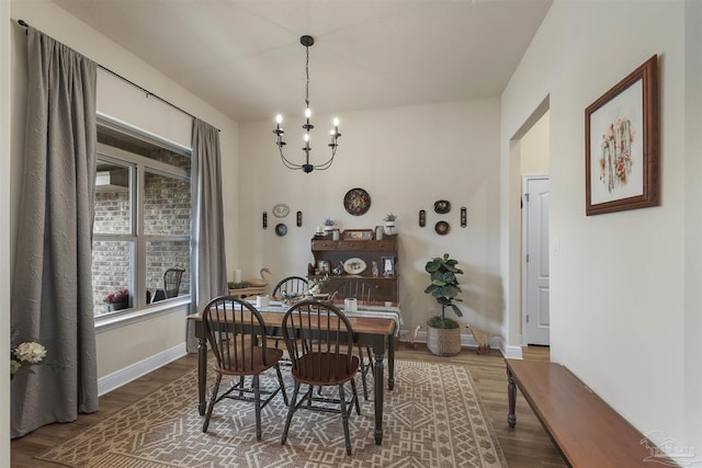 dining room featuring a notable chandelier, wood finished floors, and baseboards