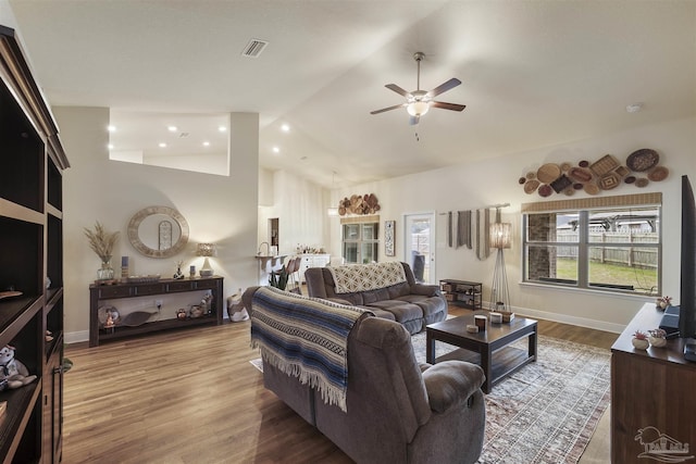 living area featuring visible vents, baseboards, a ceiling fan, wood finished floors, and high vaulted ceiling