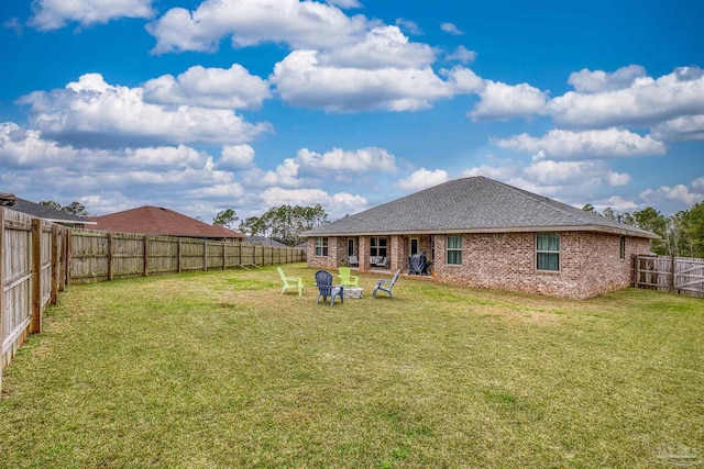 back of house with a yard, a fenced backyard, and brick siding