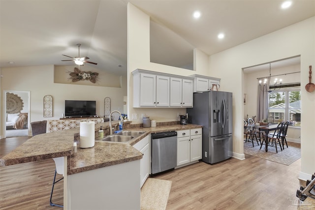 kitchen featuring a breakfast bar, appliances with stainless steel finishes, open floor plan, a sink, and a peninsula