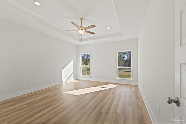 unfurnished living room featuring light wood finished floors, a tray ceiling, recessed lighting, and baseboards