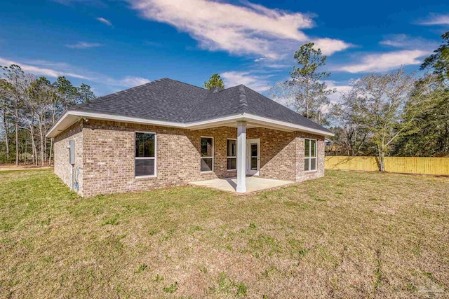 back of house with brick siding, a yard, a patio, a shingled roof, and fence