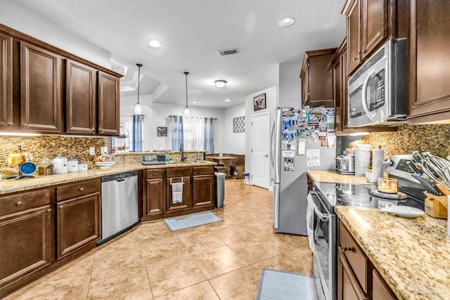 2704 Wildhurst Trl, Pace, FL 32571 - kitchen featuring stainless steel appliances, tasteful backsplash, a peninsula, light stone countertops, and dark brown cabinets