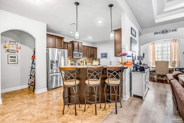 2704 Wildhurst Trl, Pace, FL 32571 - kitchen with stainless steel appliances, arched walkways, a breakfast bar, backsplash, and a peninsula
