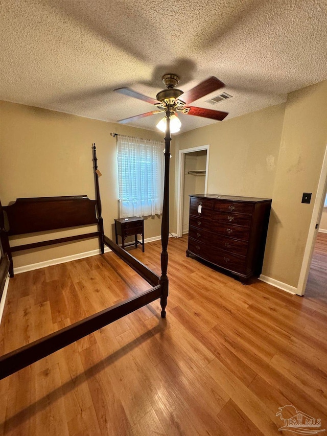 bedroom featuring ceiling fan, light hardwood / wood-style floors, and a textured ceiling