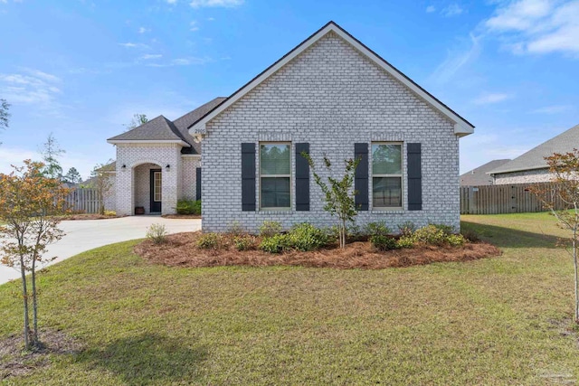view of front of home with fence, a front lawn, and brick siding