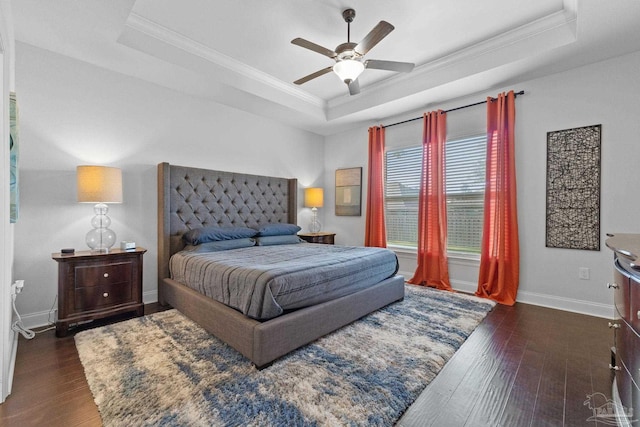 bedroom with crown molding, dark wood-style flooring, a raised ceiling, and baseboards