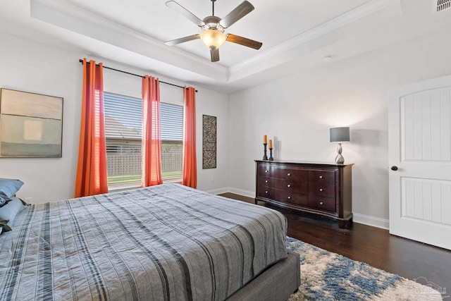 bedroom with wood finished floors, ornamental molding, ceiling fan, baseboards, and a tray ceiling