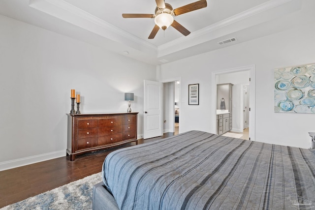 bedroom featuring a tray ceiling, visible vents, baseboards, ornamental molding, and wood finished floors