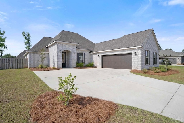 french country home with a front lawn, a garage, brick siding, concrete driveway, and fence