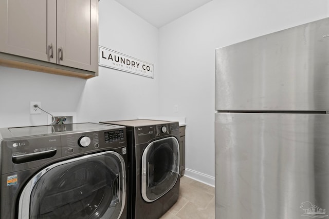 laundry area featuring baseboards, light tile patterned floors, cabinet space, and washing machine and clothes dryer