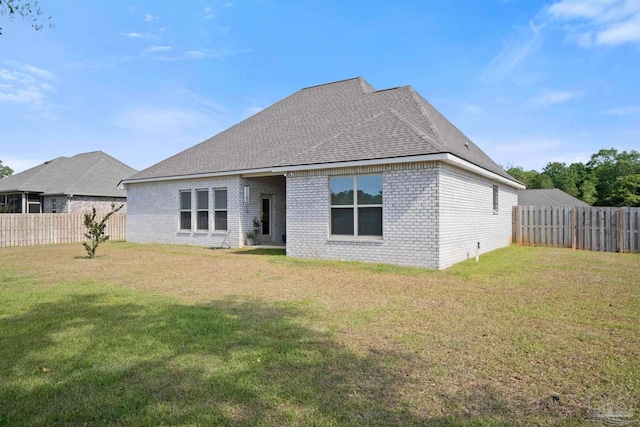 back of house featuring brick siding, a fenced backyard, and a yard