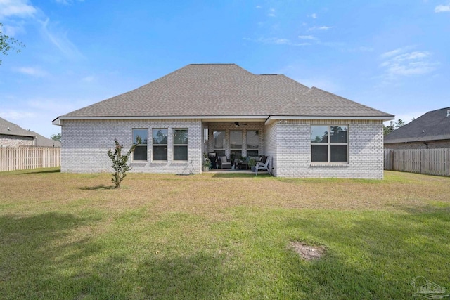 back of property with a ceiling fan, a yard, brick siding, and a fenced backyard