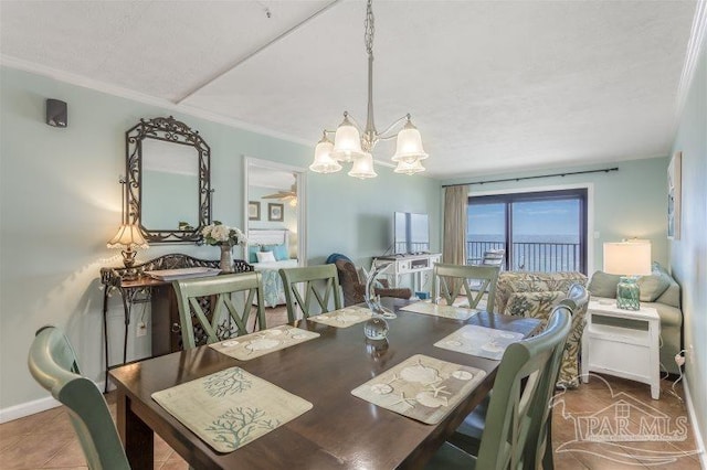 dining area featuring tile patterned flooring, crown molding, and an inviting chandelier