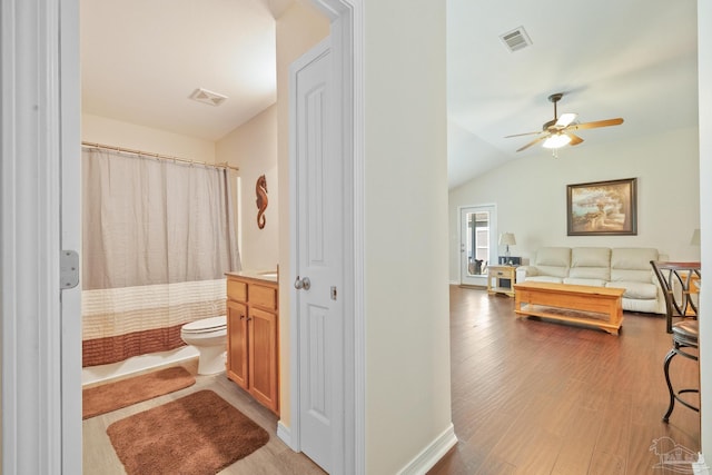 bathroom featuring toilet, vanity, hardwood / wood-style flooring, ceiling fan, and vaulted ceiling