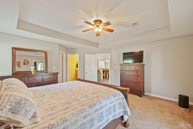 carpeted bedroom featuring ceiling fan and a tray ceiling