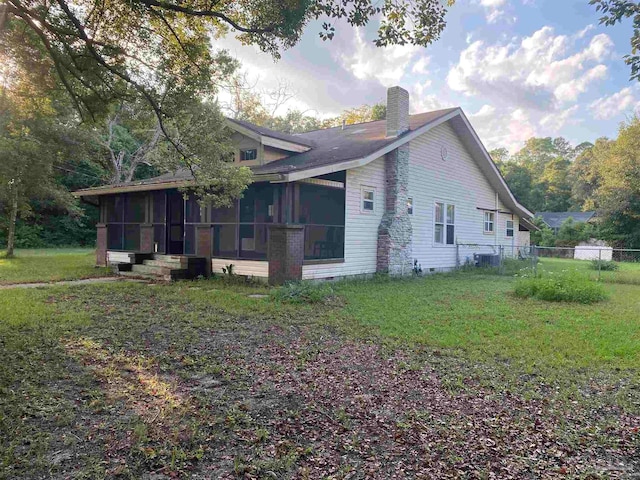 view of property exterior with cooling unit, a sunroom, and a lawn