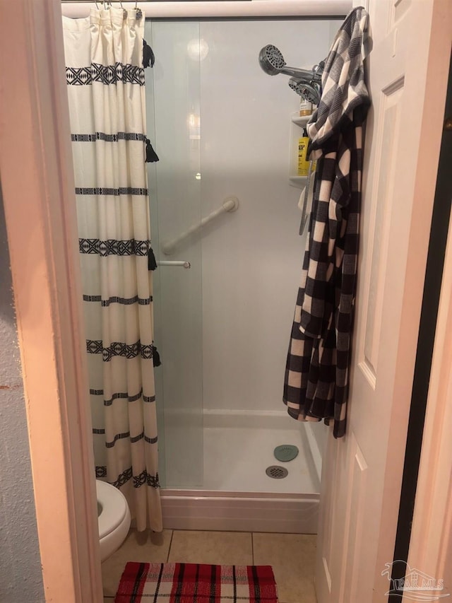 bathroom with toilet, tile patterned floors, and walk in shower