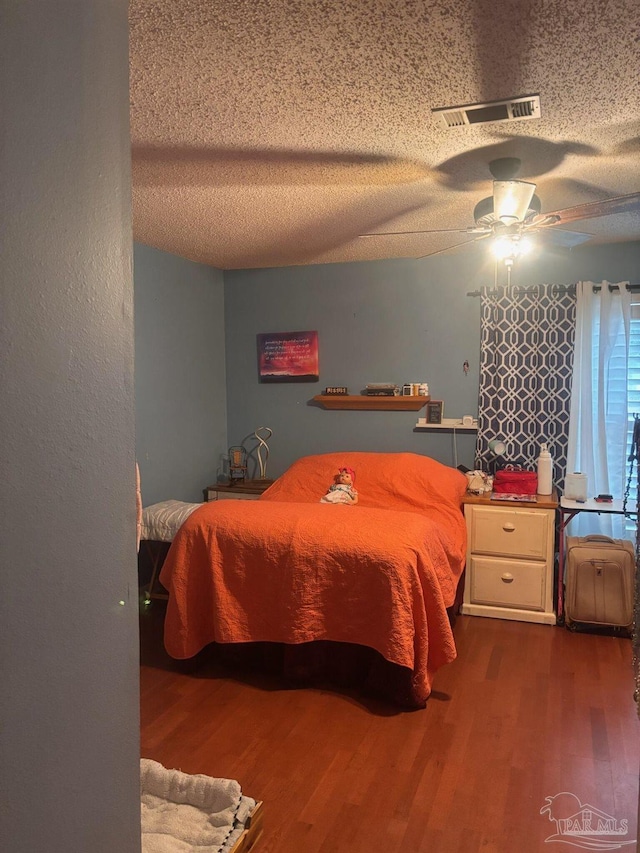 bedroom with ceiling fan, hardwood / wood-style floors, and a textured ceiling