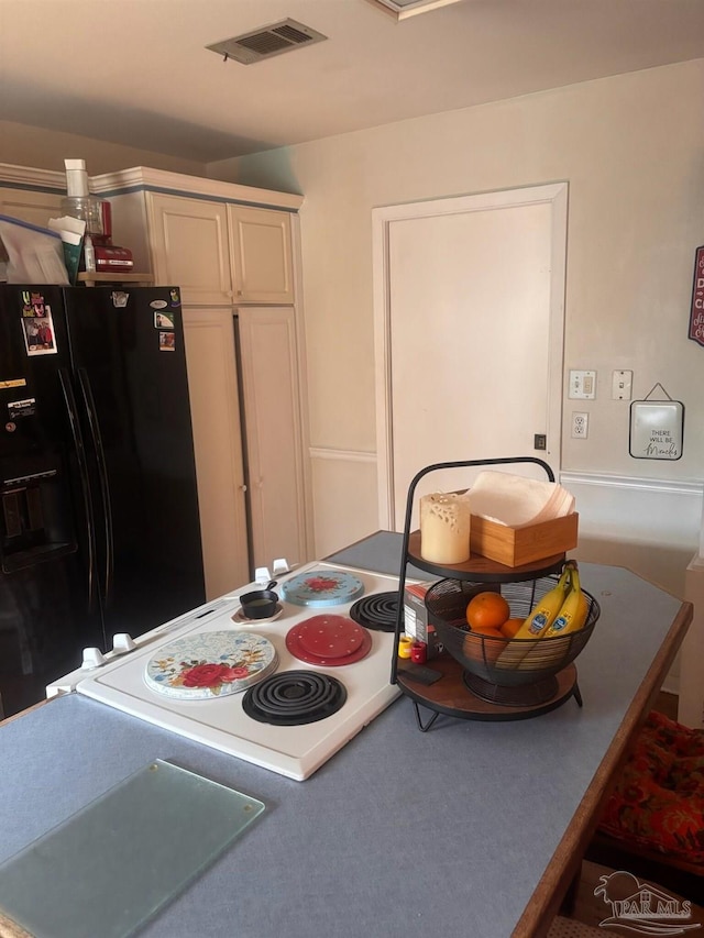 kitchen featuring black fridge and white cabinetry