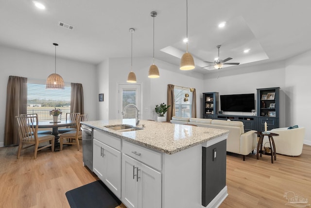 kitchen with dishwasher, sink, a tray ceiling, white cabinetry, and a kitchen island with sink