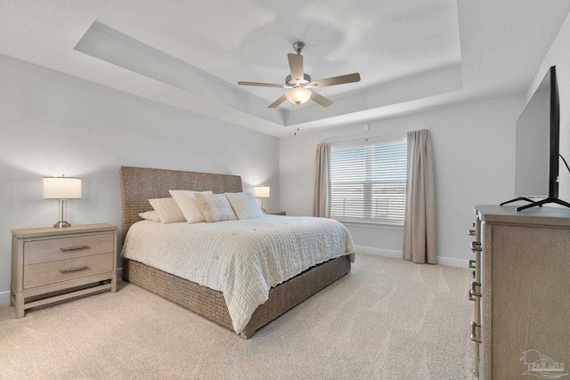 bedroom featuring ceiling fan, light carpet, and a raised ceiling