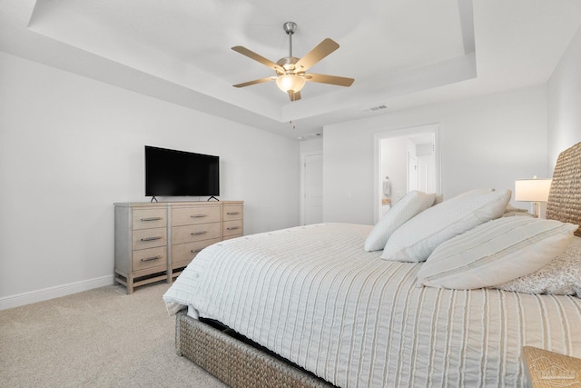 carpeted bedroom featuring ceiling fan, connected bathroom, and a raised ceiling