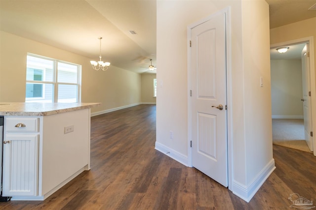 kitchen featuring dark hardwood / wood-style flooring, decorative light fixtures, white cabinetry, and ceiling fan with notable chandelier