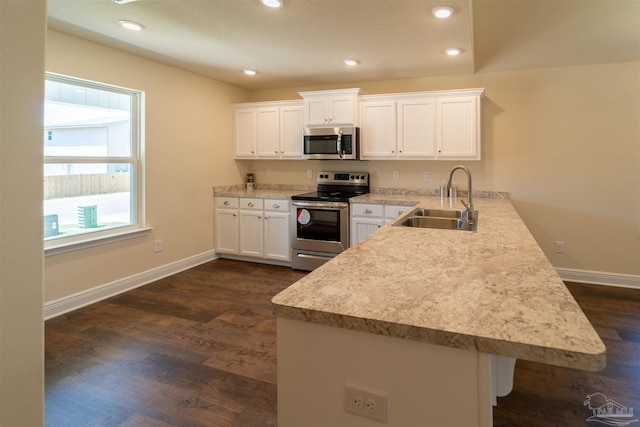 kitchen featuring appliances with stainless steel finishes, sink, dark hardwood / wood-style floors, and kitchen peninsula