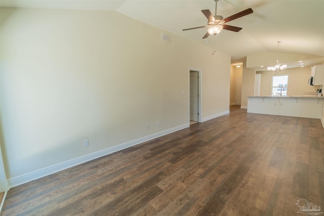 unfurnished living room with dark wood-type flooring, vaulted ceiling, and ceiling fan with notable chandelier