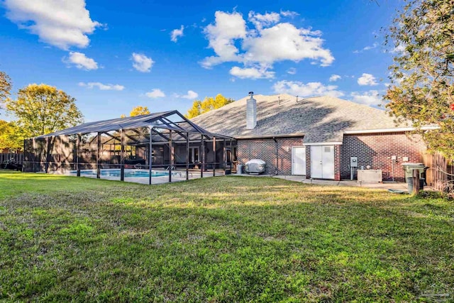 back of property featuring a fenced in pool, glass enclosure, and a yard