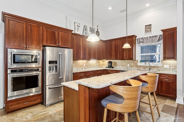 kitchen featuring light stone countertops, a kitchen island, stainless steel appliances, and decorative light fixtures