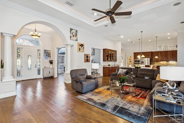 living room featuring decorative columns, crown molding, dark hardwood / wood-style flooring, and ceiling fan with notable chandelier