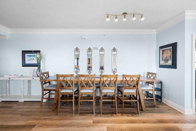 dining area with hardwood / wood-style floors, crown molding, and a textured ceiling