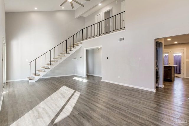 unfurnished living room featuring a towering ceiling, ceiling fan, and dark hardwood / wood-style floors