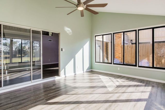 empty room with ceiling fan, wood-type flooring, a healthy amount of sunlight, and vaulted ceiling