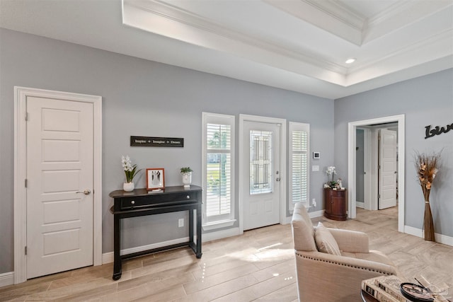 entryway with light hardwood / wood-style floors, a tray ceiling, and crown molding